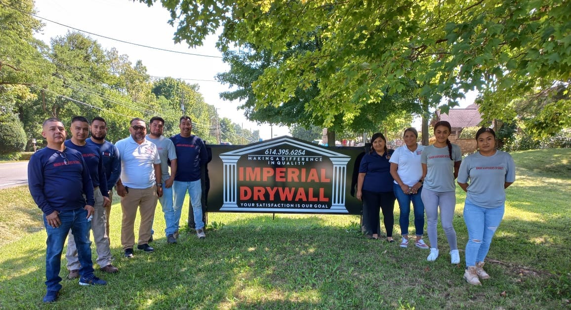 The Imperial Drywall team at the company sign